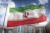 عکس با کیفیت بالا پرچم ایران در حال اهتزاز با پس زمینه آسمان و ساختمان